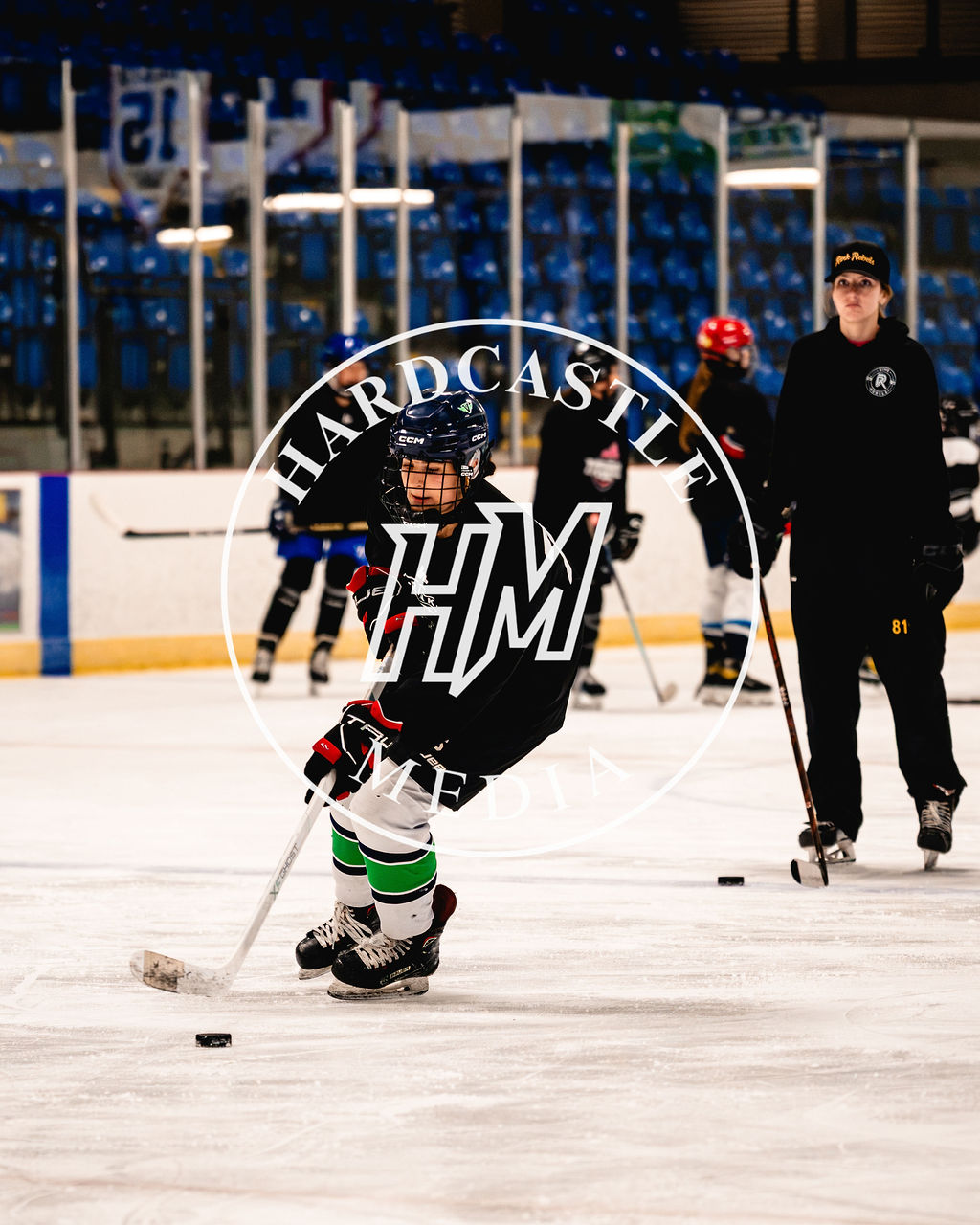 A young player practising on the ice with an athlete mentor nearby