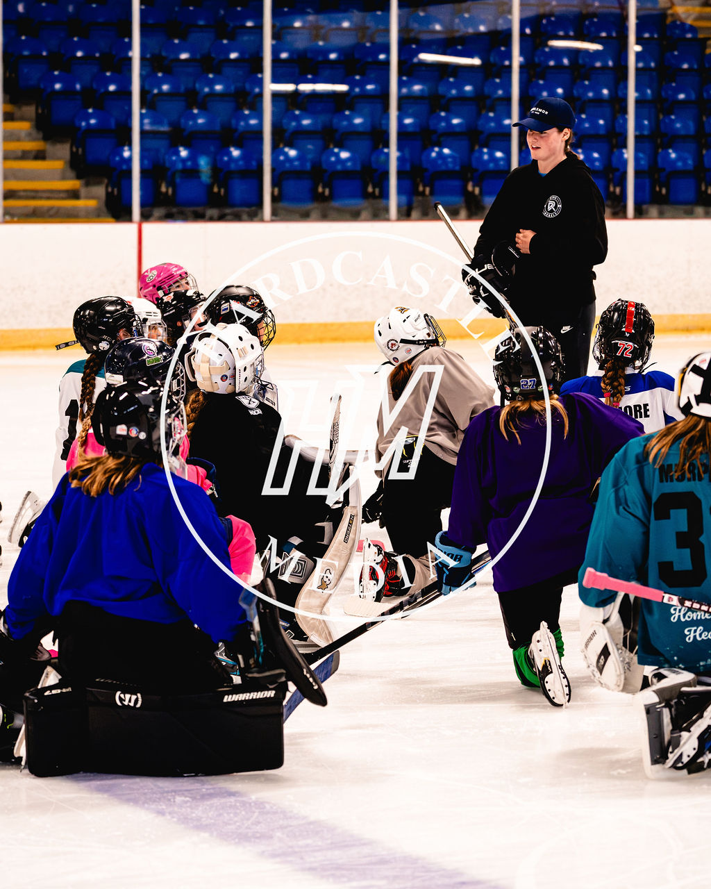 Young Rink Rebels players listening to an athlete mentor on the ice
